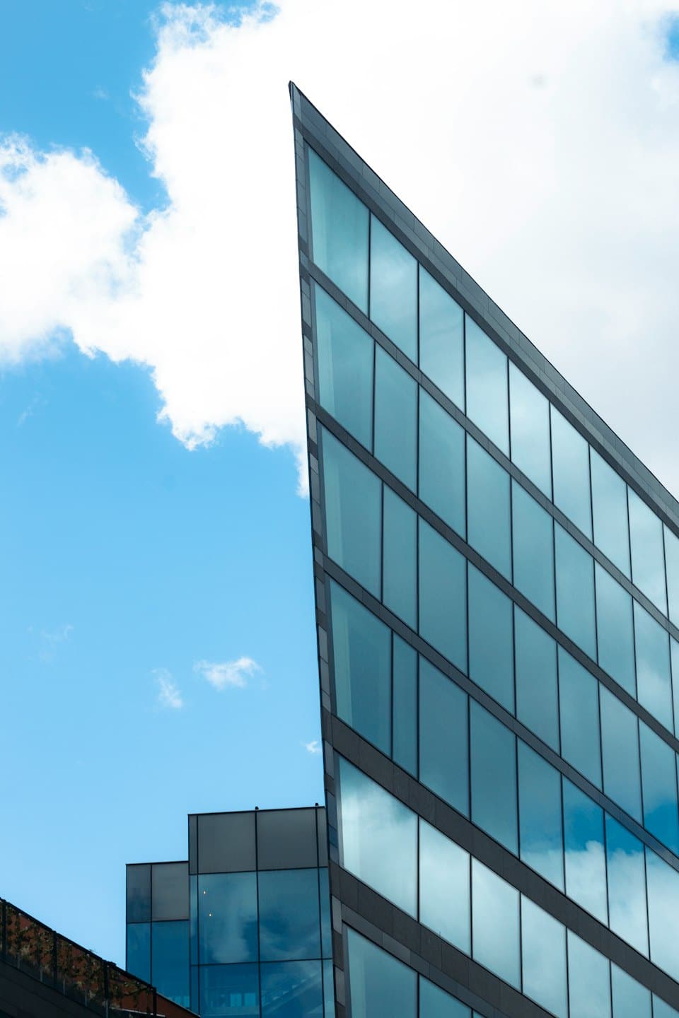 Modern glass building with angular facade under a clear sky.