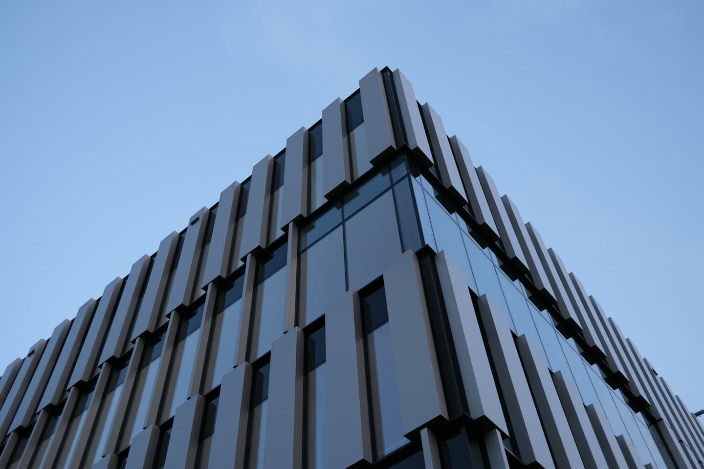 Modern office building facade with geometric metal panels and glass windows.