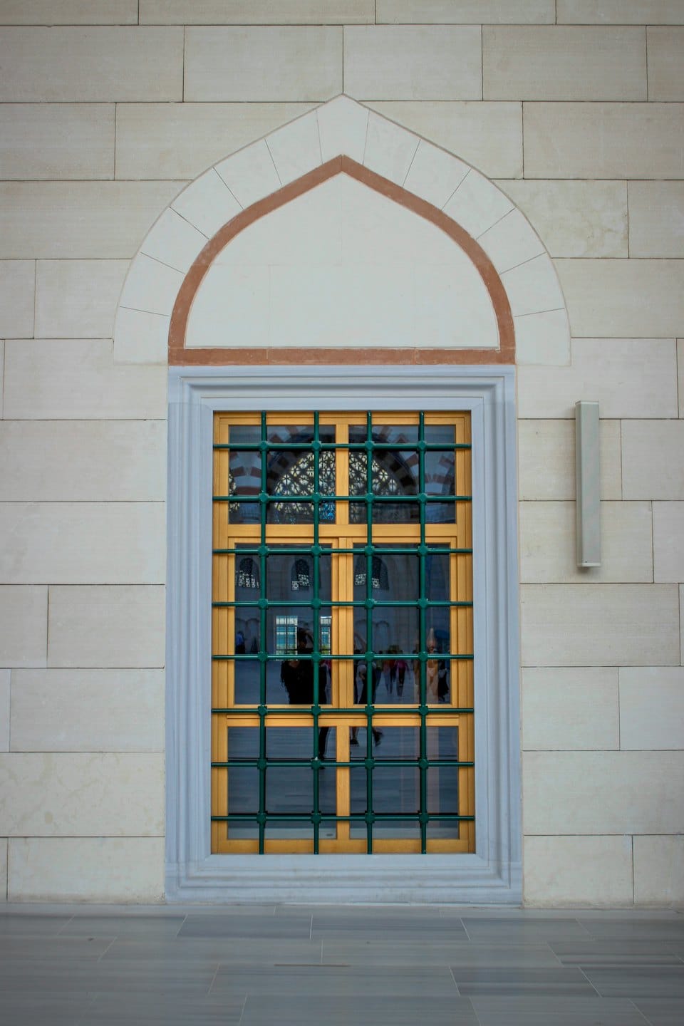 Ornate gold window with a green grille set in stone.