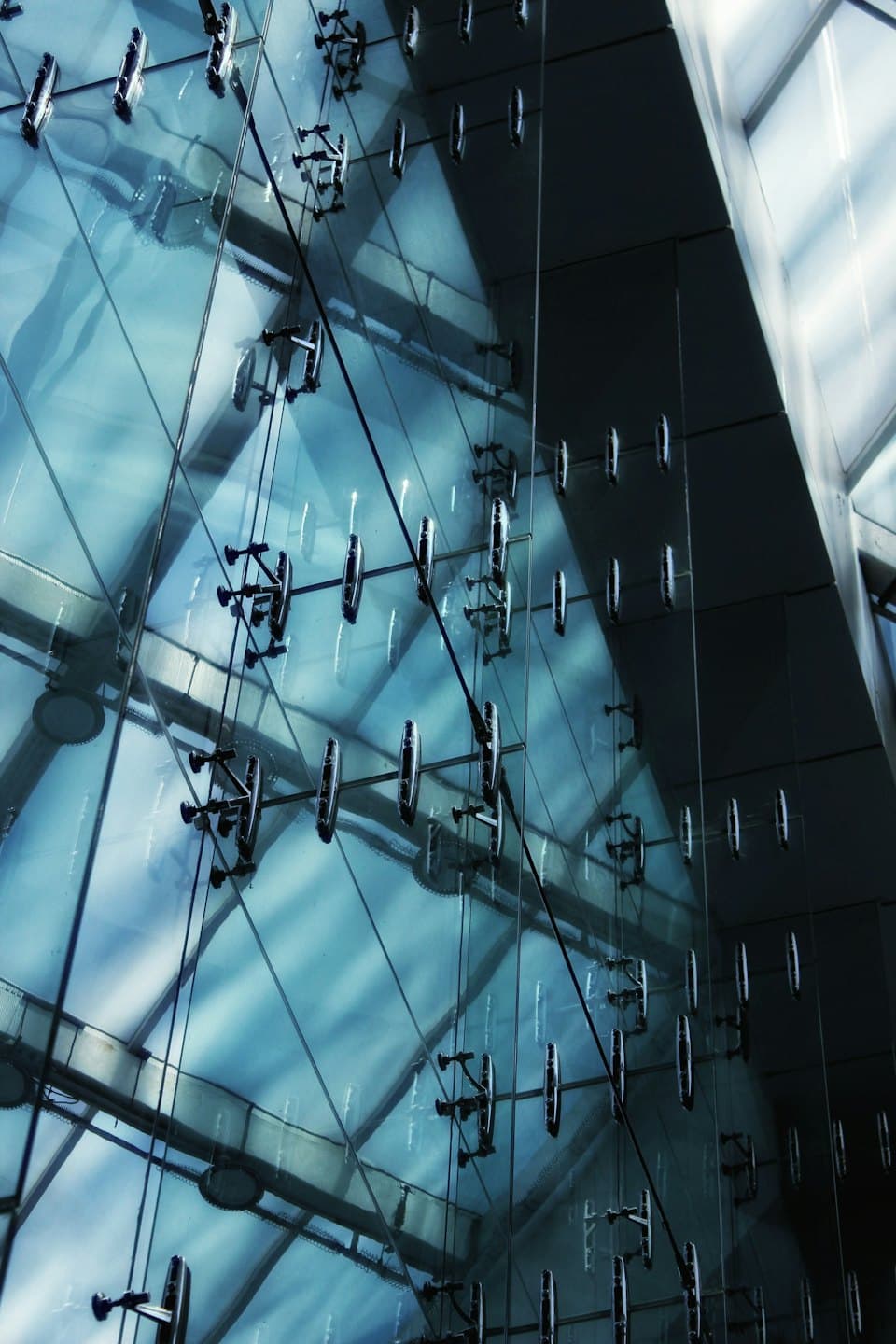 Blue glass panels held together by dark metal spider fittings.