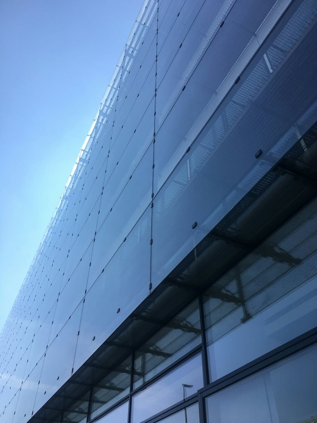 Modern glass building exterior with a reflective metal grid pattern.