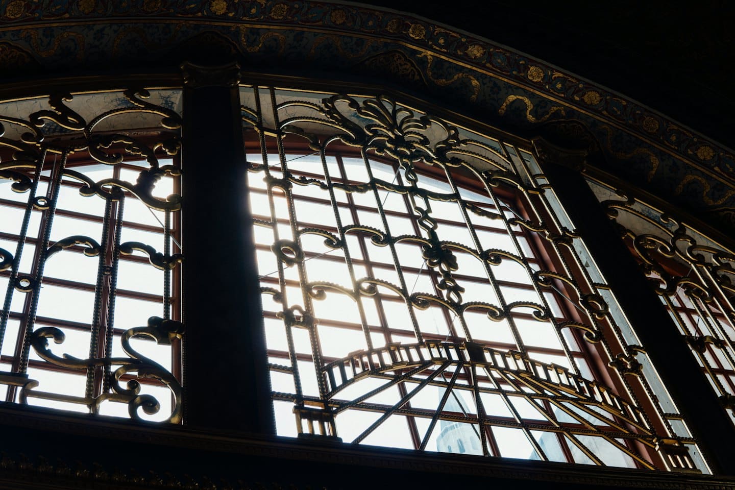 Ornate arched window with intricate gold metal grille work.