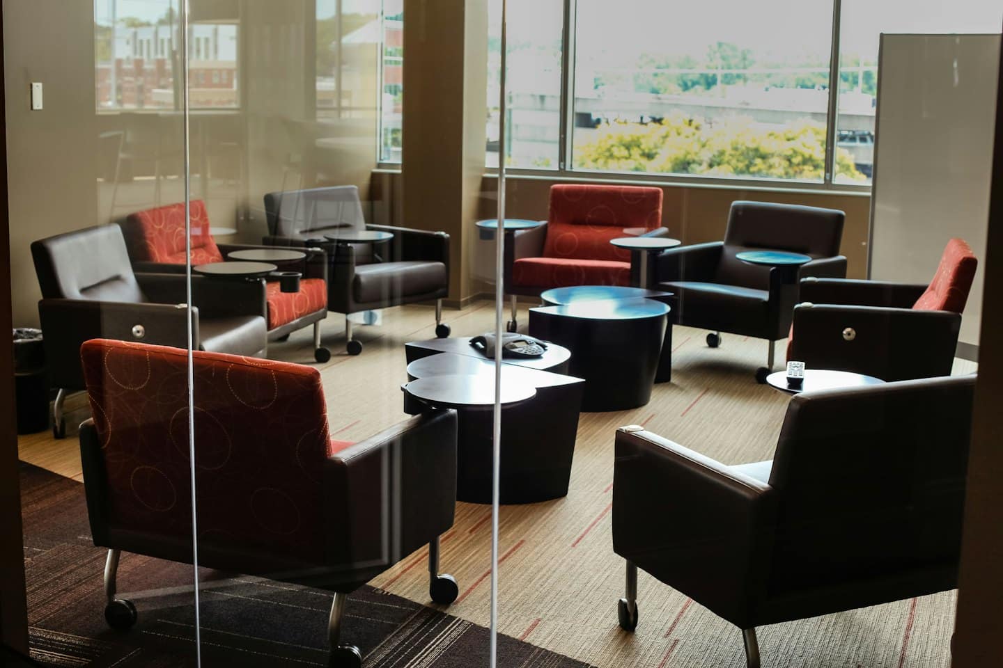 Modern meeting area with circular armchairs seen through glass.